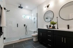 Modern full bathroom remodel with rain shower, new vanity, and quartz countertops.